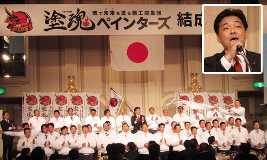 コンセプトは「塗装でできる社会貢献」。顔写真は挨拶する安田会長