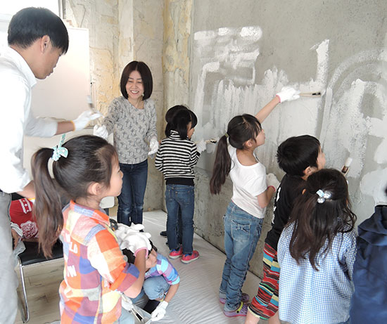 壁の塗装を楽しむ子供たち