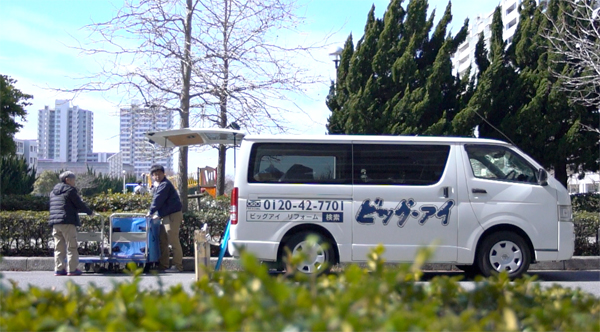 ビッグアイ　ロゴマークをつけた社用車を走らせている