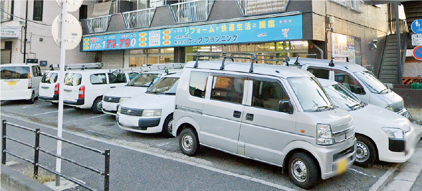 ナックプランニング　本社外観。アフターメンテナンスに向かう車が並ぶ