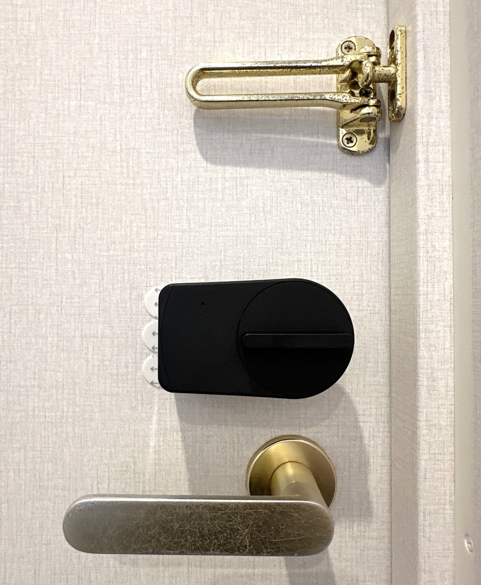 レジデンシャル不動産　室内側の玄関ドアの鍵穴部分に専用の機器を設置。スマホからアクセスすると信号を通じて、鍵が開く仕組み。